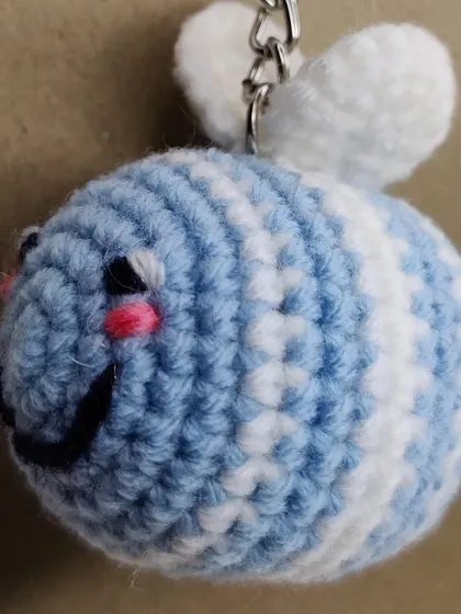 A pastel blue and white striped bee keychain.