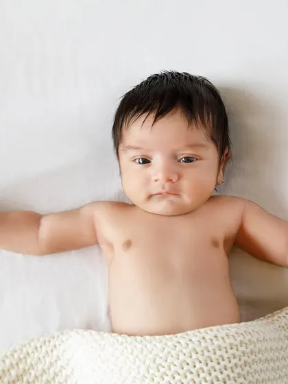 Waking up and stretching. This little one shows off their tiny chest and arms, a simple and beautiful moment from a newborn session.