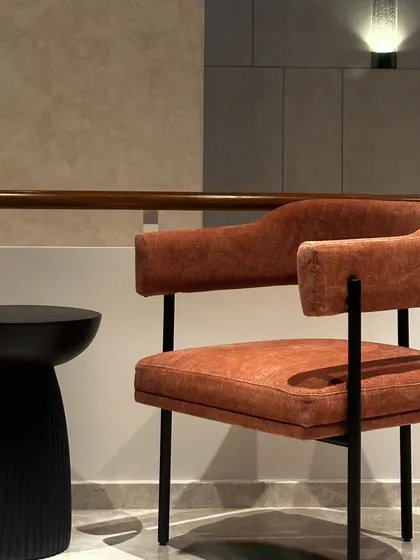 This statement chair, shown here as an inspiration piece, features a rustic orange fabric and a clean, black metal frame. It's a perfect example of how a single chair can add a pop of color and personality to a lounge space.