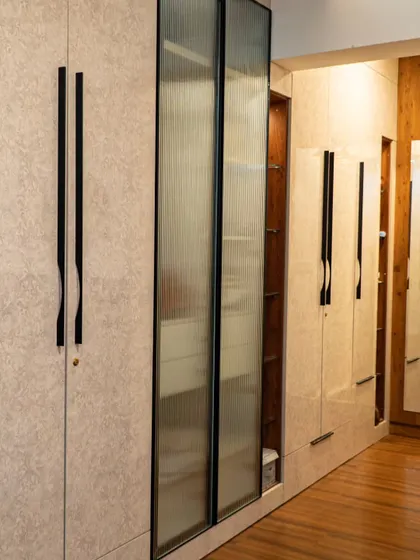 This wardrobe holds a clever secret. I designed it with a hidden, tucked-in pouf that can be pulled out for a comfortable seat at the vanity, making it a perfect example of smart, space-saving design.