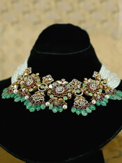 This exquisite Polki choker redefines bridal jewellery with its floral inspired design. Handcrafted with polki diamonds and cascading emerald beads, it is ideal for pairing with lehengas or saris, ensuring you shine as brightly as your special day.