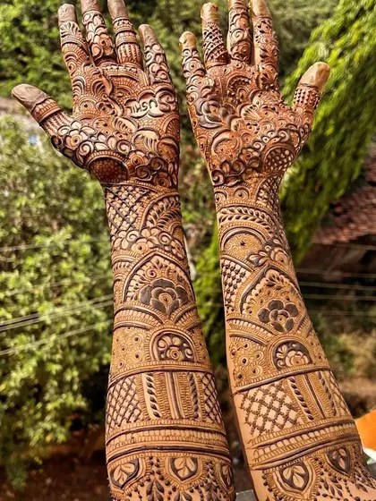 This full-coverage bridal mehendi was done outdoors, showing how the natural henna paste looks fresh. The design is filled with traditional motifs, perfect for a classic bridal look.