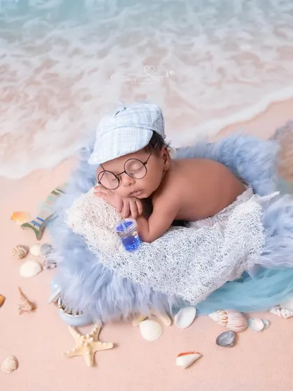 A little sailor snoozing on the beach. The cap, glasses, and tiny drink add so much personality to this creative seaside theme.