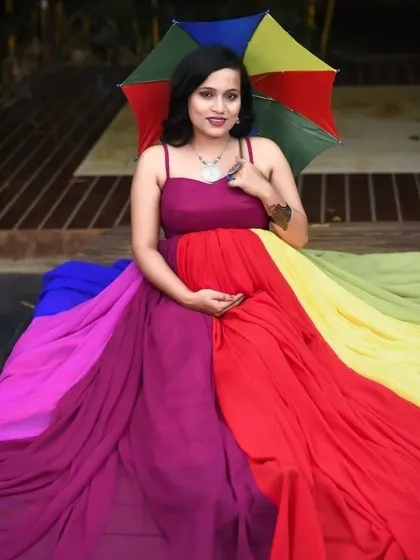 Seated portrait in the multi-colored maternity gown, showing how the vibrant fabric drapes beautifully even when sitting, ensuring you look great from every angle.
