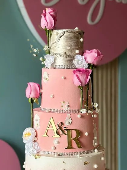 Elegance layered high. This stunning pink, silver, and white wedding cake features multiple tiers with different textures, from shimmering silver to soft pink, all adorned with fresh roses.