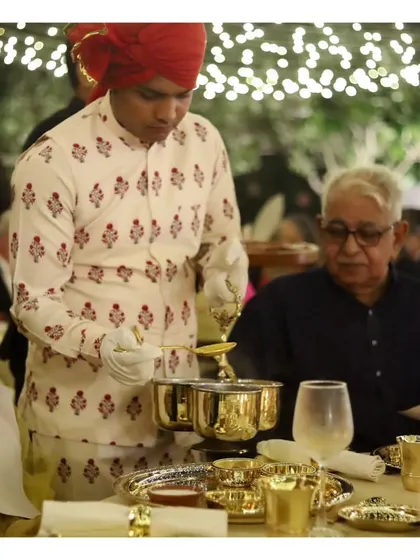 Our server attending to a guest at a traditional Indian sit-down dinner, showcasing the authentic and respectful service style we employ.