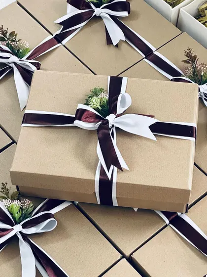 A large order of corporate gifts, elegantly packed in simple cardboard boxes with a beautiful two-toned ribbon and a touch of floral decor.