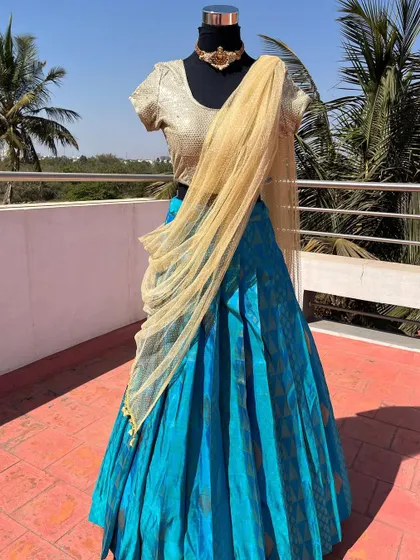 A light blue half saree with a gold sequin blouse.