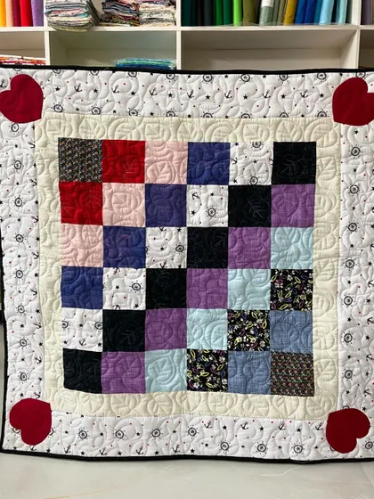 A lovely assorted baby quilt with a checkerboard center and a nautical-themed border. The four red hearts in the corners add a pop of love.