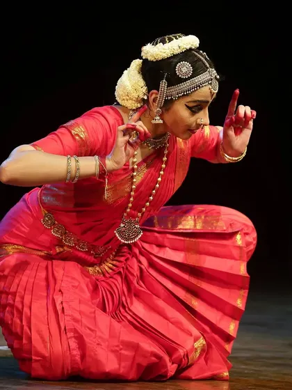 A moment of storytelling from "Venkatesha Shreesha," where the hand gesture, or mudra, signifies a question to the divine. The vibrant red costume symbolizes devotion and spiritual energy.