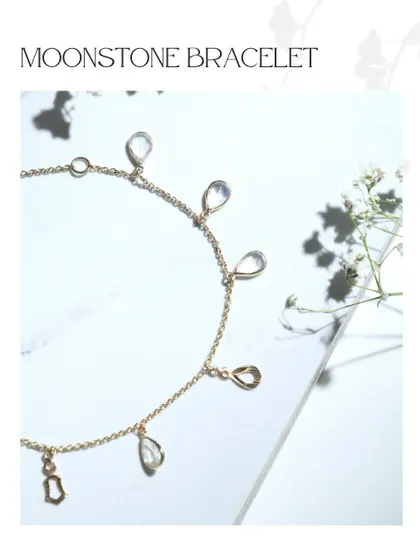 A dainty moonstone bracelet with teardrop-shaped gems and delicate gold charms. The ethereal glow of moonstone makes this piece truly special.