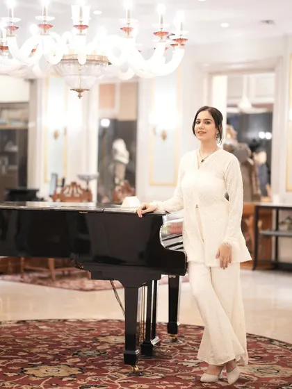 An elegant pose next to a grand piano, wearing the white co-ord set. This look is perfect for a sophisticated brunch or day event.
