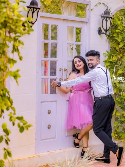 A fun, dancing pose in front of a white door. The couple's playful interaction and their stylish outfits make this a very lively and memorable shot.