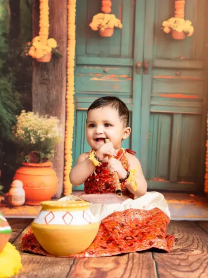 A happy smile from our little one in a vibrant Krishna-themed setting. The detailed backdrop and props create a rich visual story celebrating Indian culture.