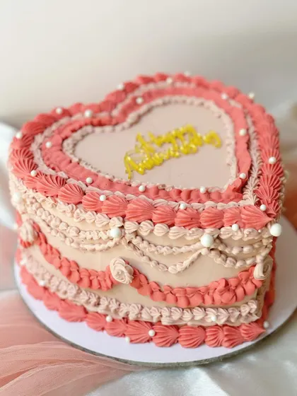 A beautiful heart-shaped cake with ombre pink Lambeth piping. The layers of detailed piping create a stunning, textured effect perfect for a romantic celebration.