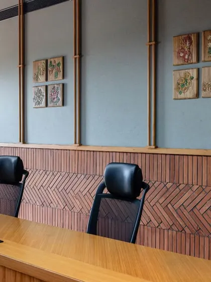 A close-up of the boardroom's brick cladding and teakwood detailing. The raw cement grouting enhances the visual texture while also serving as a sound barrier, demonstrating a fusion of function and design.