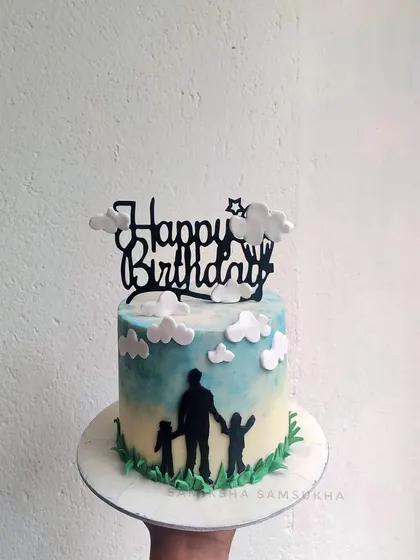 This silhouette cake tells a beautiful story. It depicts a father and his children against a painted sky, creating a touching and personal design for a birthday celebration.