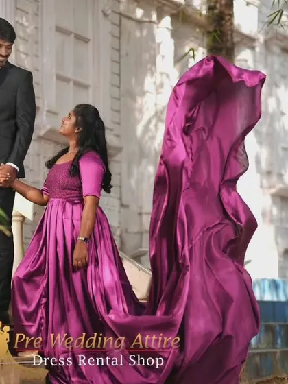 A couple on a staircase, with the woman in a satin magenta trail gown and the man in a classic black suit. The sheen of the satin fabric catches the light beautifully.