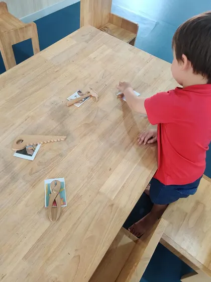 A young boy correctly matches a toy hammer and saw to their corresponding pictures. This simple game helps solidify the concepts we've discussed.
