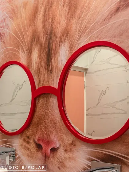 We believe even restrooms should have personality. This playful detail features a custom mirror shaped like glasses, placed over a wallpaper of a giant cat's face, adding an element of surprise and humor to the space.