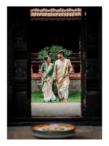 A beautifully framed shot of a couple walking through a doorway of a heritage home, with a floral arrangement in the foreground.