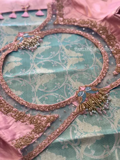 A pink and teal blouse with a sheer back and circular cutout, featuring bird motifs.