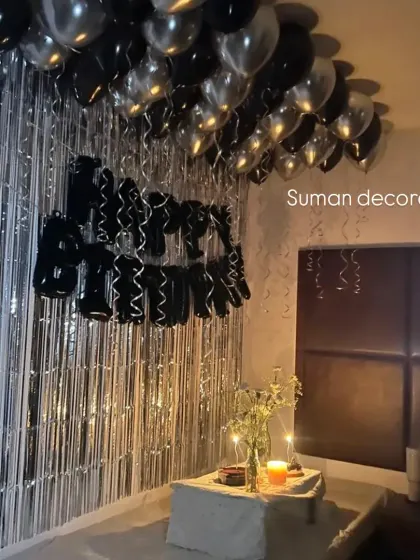 An intimate and moody birthday setup in a room. I used a silver tinsel curtain, black and silver helium balloons on the ceiling, and a 'Happy Birthday' foil banner.