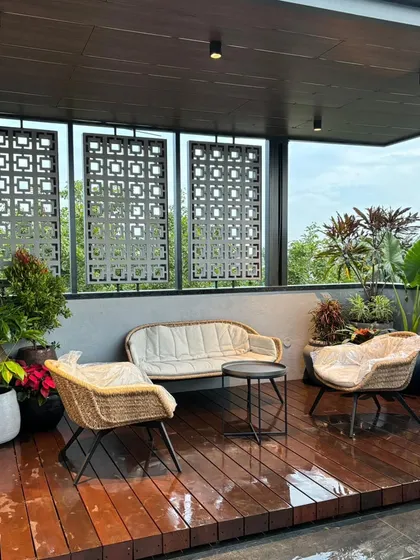 A complete terrace transformation designed for relaxation and entertaining. This space features a raised wooden deck, comfortable all-weather seating, decorative privacy screens, and a variety of tropical plants to create a private urban oasis.