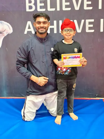 This young gymnast in his turban proudly holds his certificate, a great moment of achievement.
