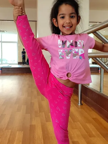 This young gymnast is mastering her standing split, a testament to her hard work and dedication to flexibility training.