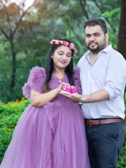 A tender moment captured as the parents-to-be look down at a tiny pair of pink shoes they are holding together. The mother's lavender tulle dress adds a fairy-tale touch.