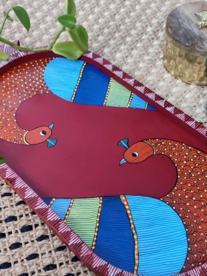 An elegant oval tray hand-painted with a colorful peacock design. The intricate patterns and vibrant colors make this a standout piece for your coffee table or for serving special treats.