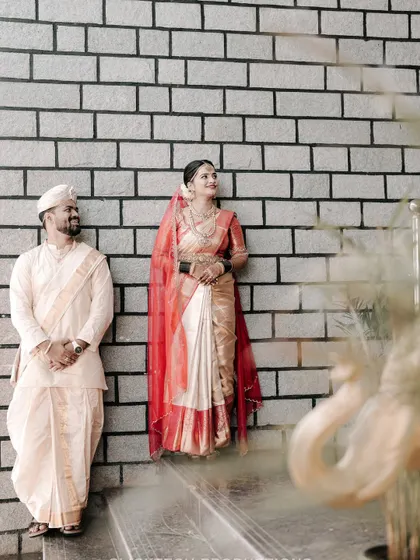 A stylishly composed shot of the couple against a modern brick wall, blending traditional attire with a contemporary background.
