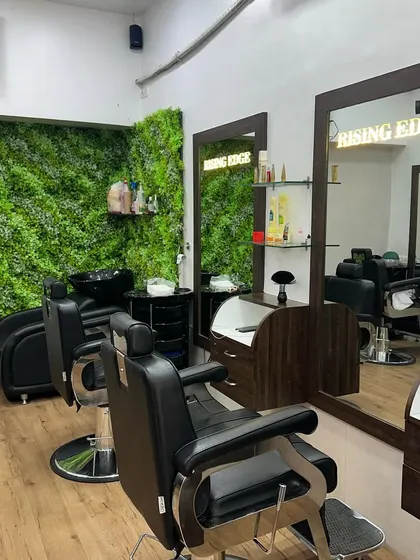 My salon is equipped with modern chairs and a clean, organized setup. The green wall adds a touch of nature and calm to the atmosphere.