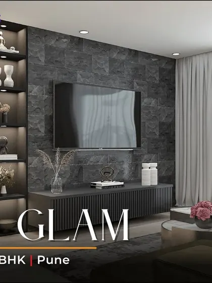 The title card for our 'Zen Glam' 3BHK project in Pune, showcasing the living room's dark stone TV wall, elegant chandelier, and comfortable seating, perfect for relaxing in style.