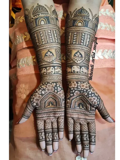 A grand design with architectural domes on the arms and floral archways on the palms. This mehendi has a very regal and structured feel.