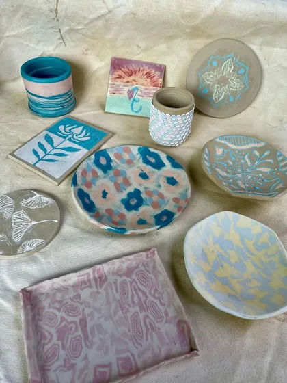 A colorful flat-lay of various student pieces, showcasing different techniques like sgraffito, marbling with colored slips, and painting. This is the result of our new course on slips and colored clays.