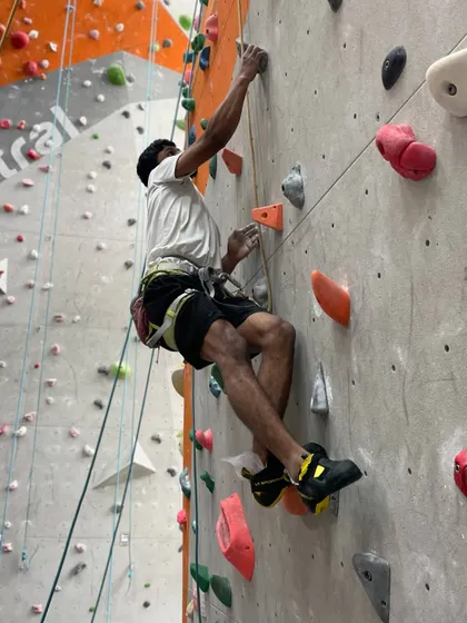 A climber makes his way up a route, showcasing the dynamic movement and full body engagement the sport requires.
