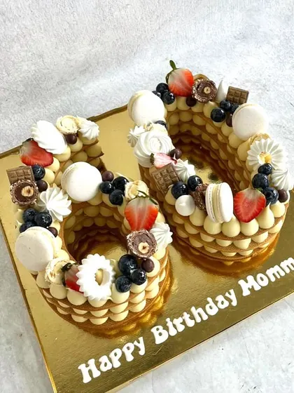 A cream tart cake for a 60th birthday. This one is decorated with macarons, fresh berries, and little pieces of chocolate.