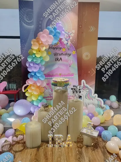 A magical unicorn themed birthday decoration with a pastel rainbow balloon arch and a unicorn cutout.