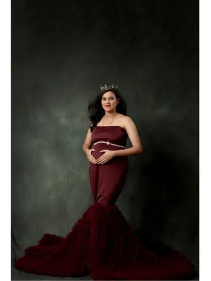 A regal portrait of the expecting mother wearing a crown with the wine-red gown, capturing the queen she is.