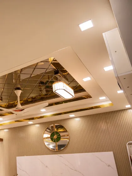 An intricate mirrored and gold-finish false ceiling, with integrated smart lighting to create a luxurious and reflective ambiance.