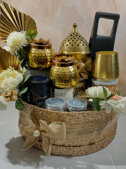 The full Glitterati gift hamper, a perfect example of luxurious festive gifting. The shimmering gold basket is packed with a brass burner, candles, and a wide selection of gourmet food items.