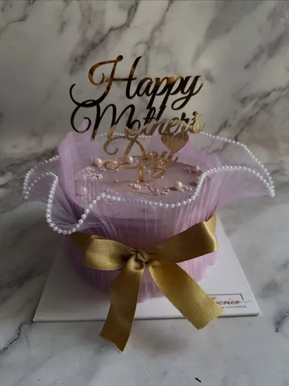 A special Mother's Day cake wrapped in elegant purple tulle and tied with a gold ribbon, making it the perfect gift for the sweetest woman in your life.