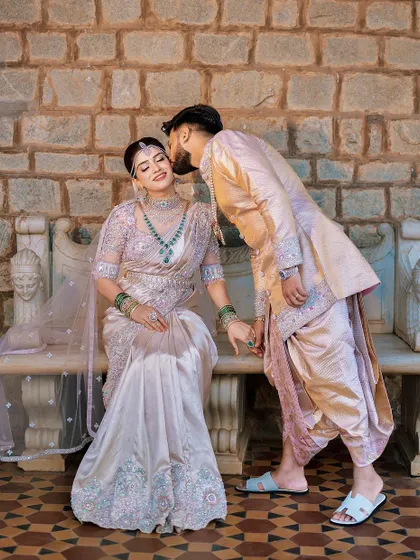 This groom's pastel sherwani, paired with a matching dhoti and light blue slippers, is a perfect example of a modern, coordinated look. The groom gives his bride a sweet kiss on the cheek.