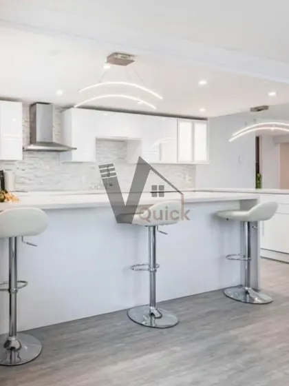 A perfect example of an open-plan kitchen with a breakfast bar. The clean white cabinets and countertop are paired with modern bar stools, creating a casual dining spot that is both stylish and practical for everyday life.