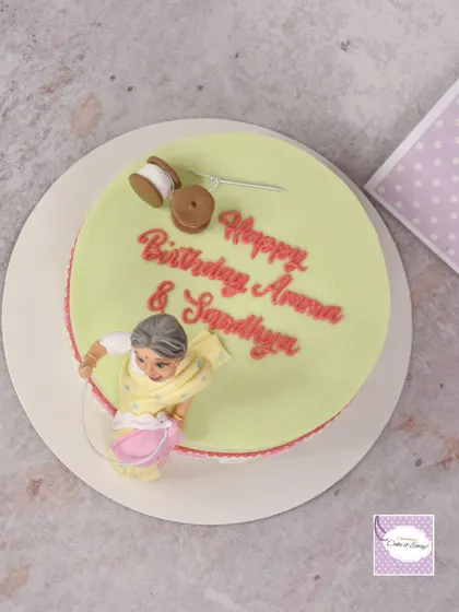 A top-down view of the sewing cake, highlighting the fondant spools of thread and the hand-piped birthday message.