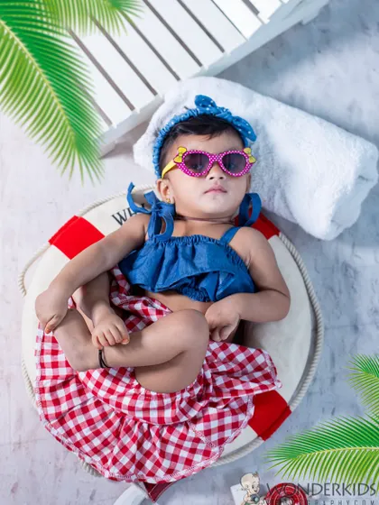 This baby is ready for the beach with her cool sunglasses and stylish outfit. Lying on a lifebuoy prop, she looks like a tiny fashionista enjoying a sunny day.