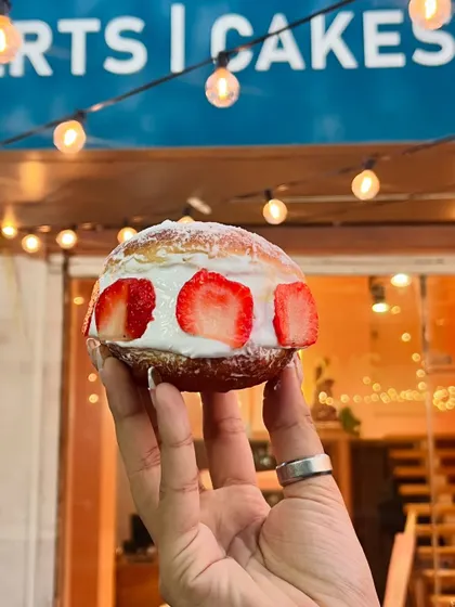 A festive Strawberry Berliner held up against the warm lights of the cafe. It’s a perfect treat to celebrate the holiday season.
