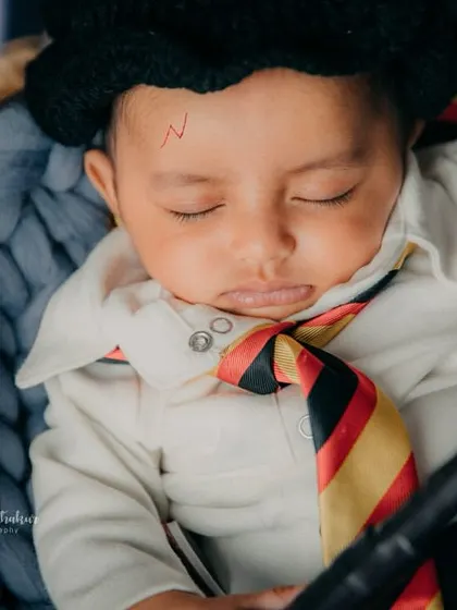 A close-up of baby Harry, complete with the iconic scar and Gryffindor scarf. He's sleeping soundly, probably dreaming of Hogwarts.